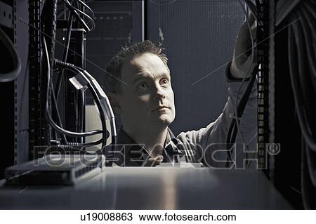 Stock Image - Man working in server room. Fotosearch