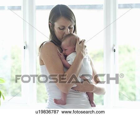 Mother holding infant son by window View Large Photo Image Stock Photo - Mother holding infant son by window. Fotosearch