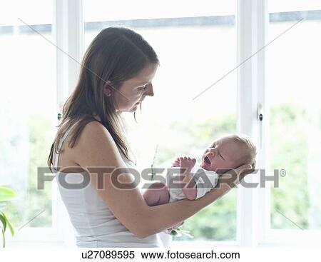Mother holding infant son by window View Large Photo Image Stock Photography - Mother holding infant son by window. Fotosearch