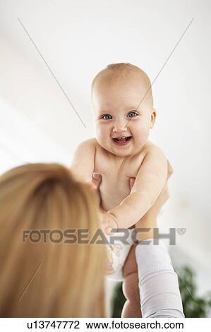 Stock Image - Mother holding laughing baby girl. Fotosearch