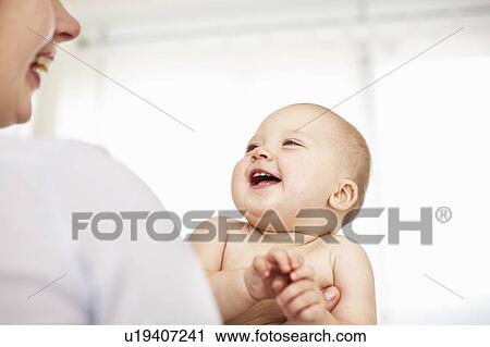 Stock Image - Mother holding laughing baby girl. Fotosearch
