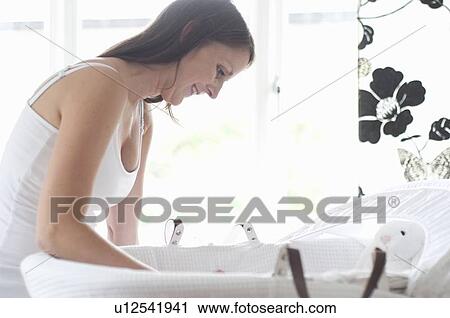 Stock Image - Mother placing baby in crib. Fotosearch