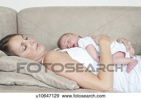 Mother sleeping with infant son on sofa View Large Photo Image Stock Photo - Mother sleeping with infant son on sofa. Fotosearch