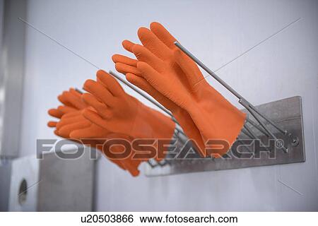 Stock Photograph - Orange gloves on drying rack. Fotosearch
