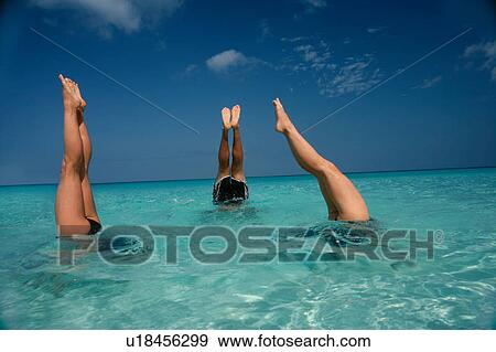 Stock Photo - People in headstands in tropical water. Fotosearch