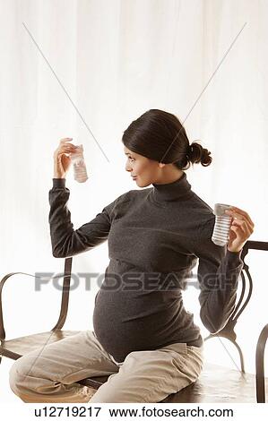Stock Photo - Pregnant woman examining baby socks. Fotosearch