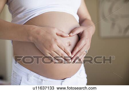 Pregnant woman making heart shape View Large Photo Image Stock Image - Pregnant woman making heart shape. Fotosearch