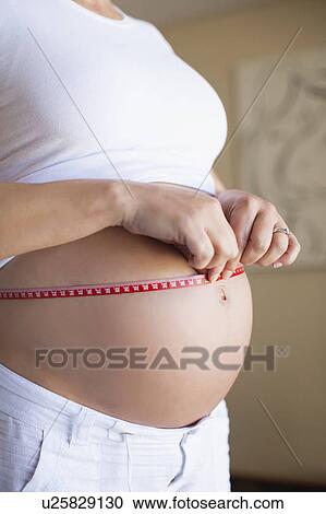 Stock Image - Pregnant woman measuring belly. Fotosearch