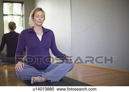 Stock Image - Pregnant woman practicing yoga in studio. Fotosearch