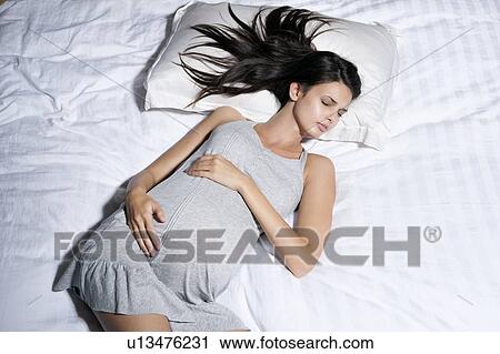 Stock Image - Pregnant woman sleeping in bed. Fotosearch