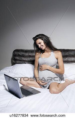 Pregnant woman using laptop in bed View Large Photo Image Picture - Pregnant woman using laptop in bed. Fotosearch