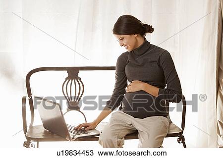 Stock Image - Pregnant woman using laptop. Fotosearch