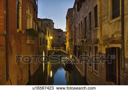 Stock Image - Rowboat and buildings on urban canal. Fotosearch