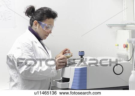 Stock Photograph - Scientist using machinery in lab. Fotosearch