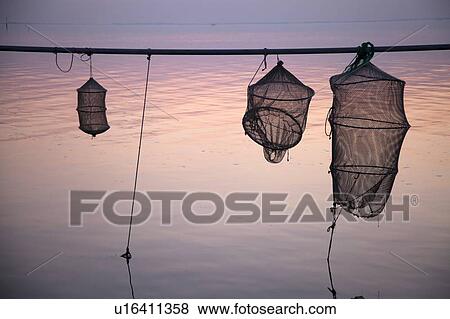 Silhouette of fishing nets over still water View Large Photo Image Stock Photo - Silhouette of fishing nets over still water. Fotosearch