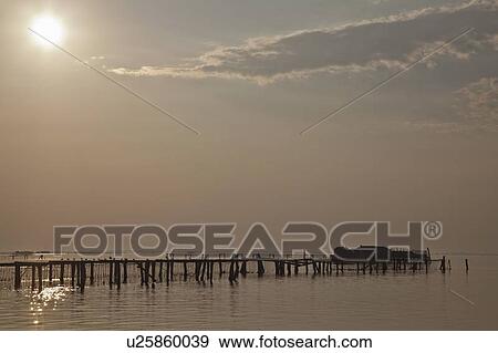 Stock Photo - Silhouette of wooden pier on water. Fotosearch