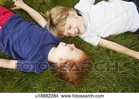 Picture - Smiling children laying in grass together. Fotosearch