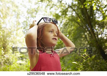 Stock Photo - Smiling girl playing with sunglasses. Fotosearch