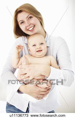 Stock Image - Smiling mother holding daughter. Fotosearch