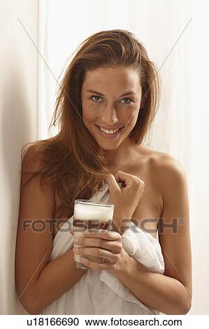 Stock Image - Smiling woman in sheet drinking coffee. Fotosearch