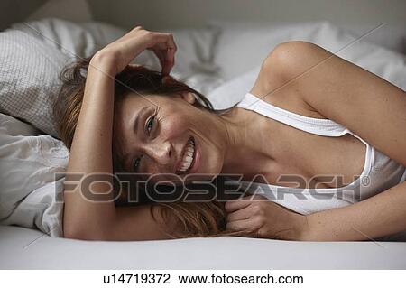 Smiling woman laying on bed View Large Photo Image Stock Image - Smiling woman laying on bed. Fotosearch