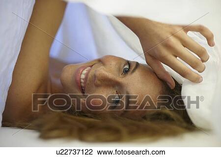 Smiling woman laying under covers View Large Photo Image Stock Image - Smiling woman laying under covers. Fotosearch