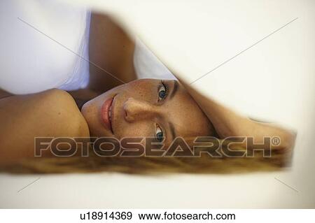 Smiling woman laying under covers View Large Photo Image Stock Photo - Smiling woman laying under covers. Fotosearch