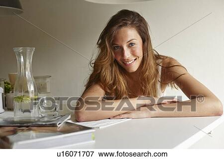 Smiling woman leaning on table View Large Photo Image Stock Photo - Smiling woman leaning on table. Fotosearch