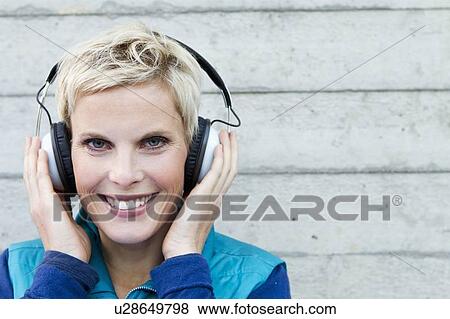 Stock Photo - Smiling woman listening to headphones. Fotosearch
