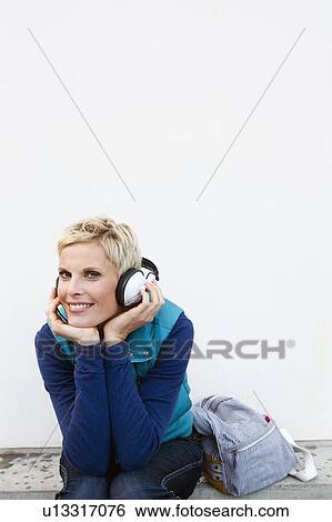 Smiling woman listening to headphones View Large Photo Image Stock Photograph - Smiling woman listening to headphones. Fotosearch