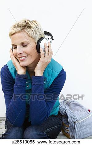 Stock Photography - Smiling woman listening to headphones. Fotosearch