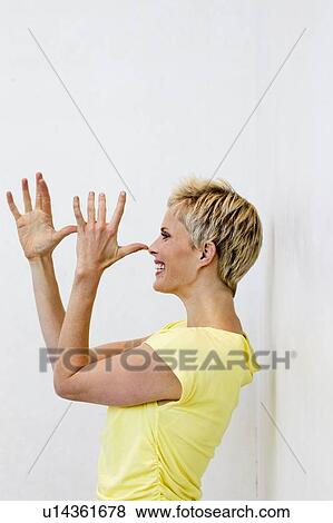Smiling woman making face with hands View Large Photo Image Stock Photo - Smiling woman making face with hands. Fotosearch