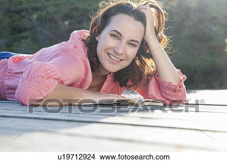 Smiling woman reading on deck View Large Photo Image Picture - Smiling woman reading on deck. Fotosearch