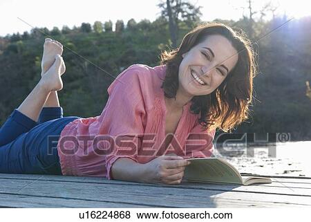 Stock Photo - Smiling woman reading on deck. Fotosearch