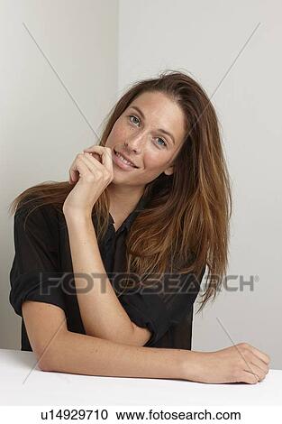 Smiling woman sitting at desk View Large Photo Image Stock Image - Smiling woman sitting at desk. Fotosearch