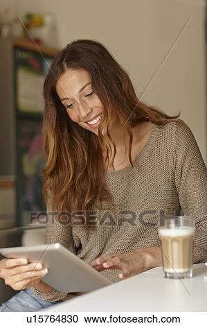 Stock Image - Smiling woman using tablet computer. Fotosearch