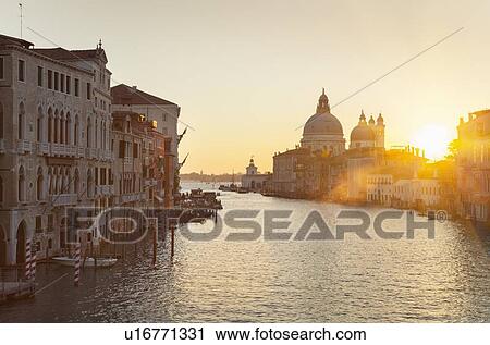 Sun setting over city buildings on canal View Large Photo Image Stock Image - Sun setting over city buildings on canal. Fotosearch