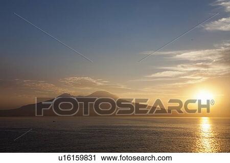 Stock Image - Sun setting over still water. Fotosearch