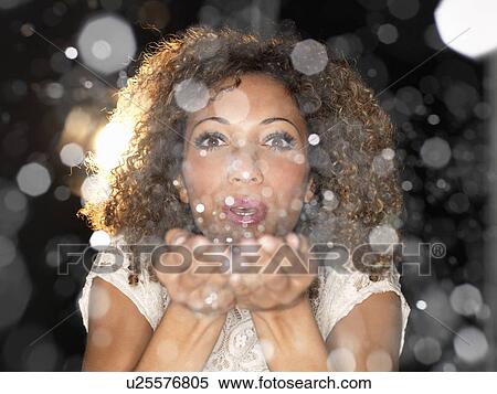 Stock Photography - Woman blowing confetti from hands. Fotosearch