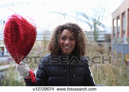 Woman carrying heart shaped balloon View Large Photo Image Picture - Woman carrying heart shaped balloon. Fotosearch