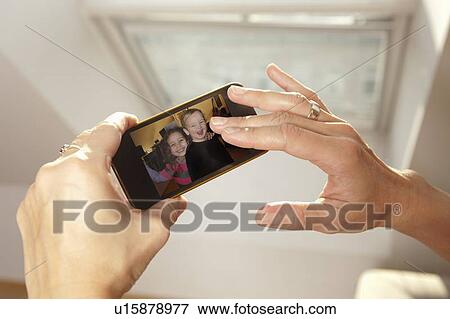Stock Photo - Woman examining picture on cell phone. Fotosearch