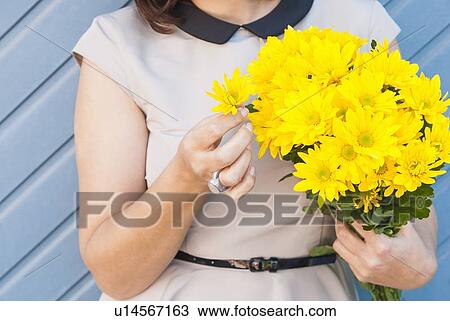 Stock Image - Woman holding bouquet of yellow flowers. Fotosearch