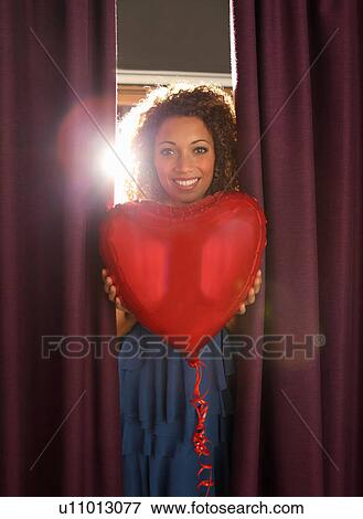 Woman holding heart shaped balloon View Large Photo Image Stock Photo - Woman holding heart shaped balloon. Fotosearch