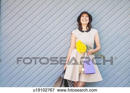 Stock Photo - Woman holding shopping bags outdoors. Fotosearch