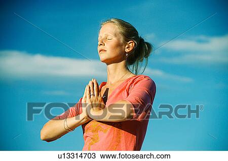 Woman meditating under blue sky View Large Photo Image Stock Image - Woman meditating under blue sky. Fotosearch