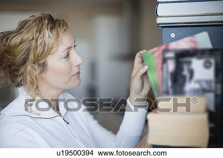 Woman organizing bookshelf View Large Photo Image Picture - Woman organizing bookshelf. Fotosearch