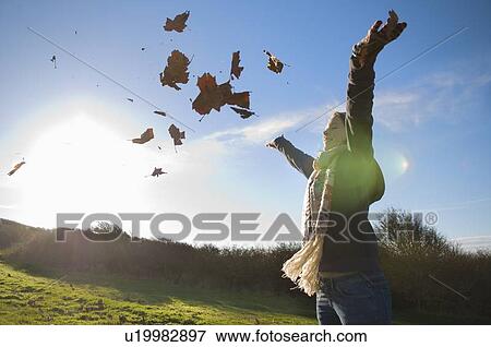 Woman playing in autumn leaves View Large Photo Image Stock Photo - Woman playing in autumn leaves. Fotosearch