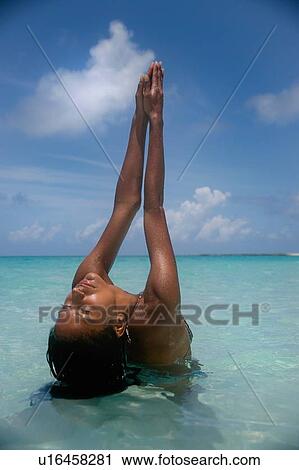 Stock Image - Woman practicing yoga on tropical beach. Fotosearch