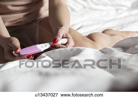 Woman reading pregnancy test on bed View Large Photo Image Stock Photo - Woman reading pregnancy test on bed. Fotosearch