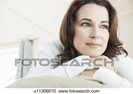 Woman relaxing on sofa in living room View Large Photo Image Stock Image - Woman relaxing on sofa in living room. Fotosearch